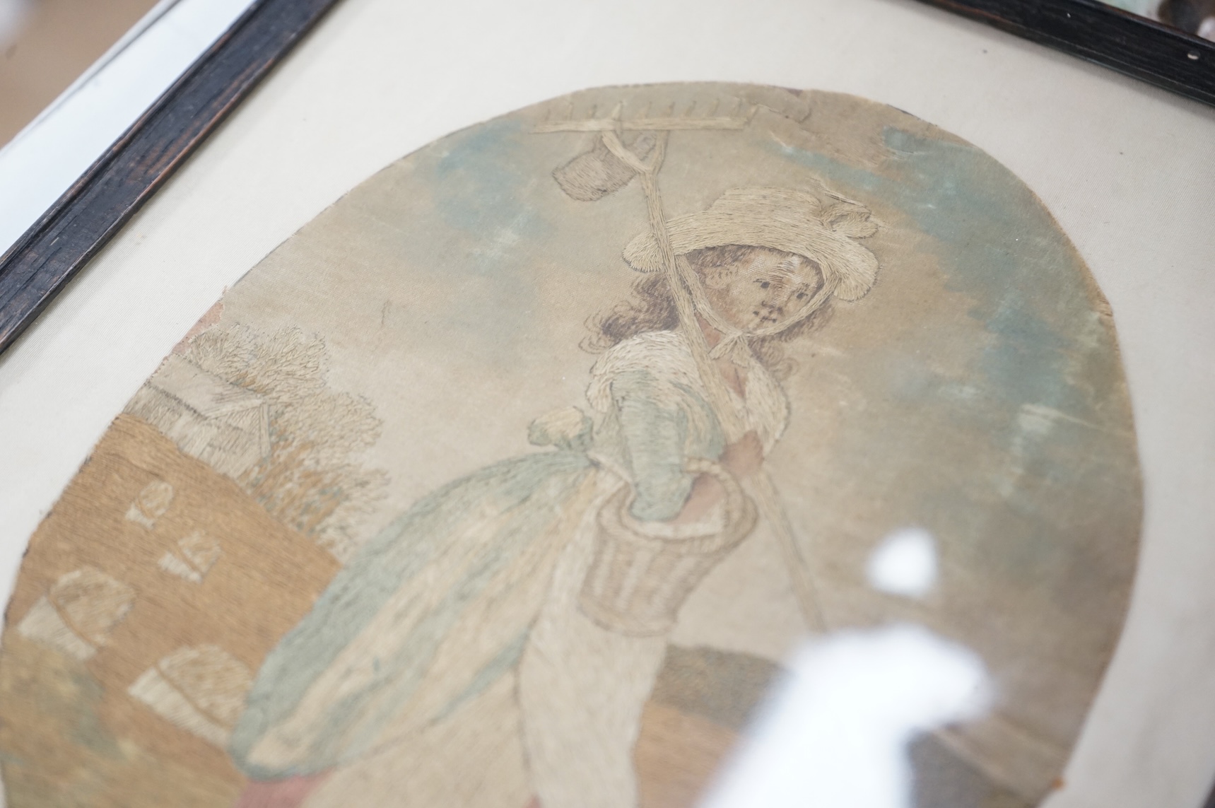 An 18th century coloured silkwork picture of a female farm hand, framed, 20cm high